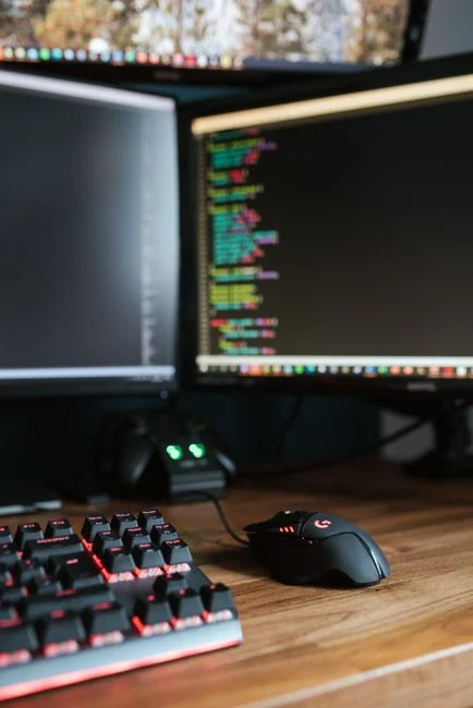 Vue arrière d’un freelance masculin anonyme, en tenue décontractée, assis à une table et travaillant sur un projet sur ordinateur portable dans une pièce lumineuse en journée