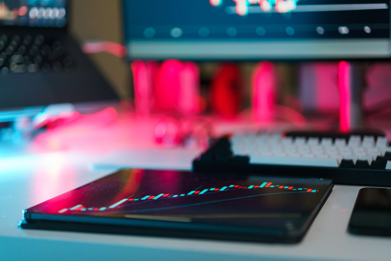 Configuration de trading high-tech avec des graphiques sur des écrans de tablette et d’ordinateur, illustrant l’analyse de données et les tendances financières.